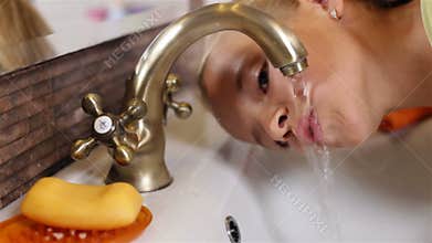 Child drinks water from the bathroom faucet