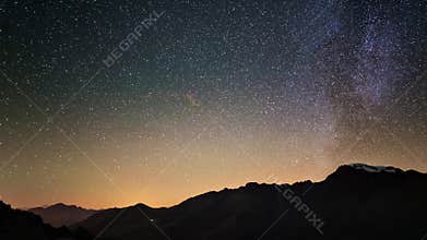 Scenic meteor explosion with stardust during time lapse of the Milky Way and the starry sky rotating over the Alps.