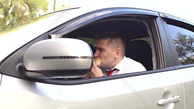 Businessman eating a Burger sitting in the car.