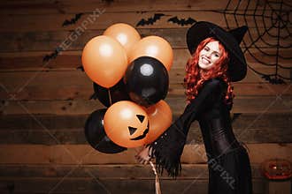 Halloween Witch Concept - Beautiful caucasian woman in witch costumes celebrating Halloween posing with posing with orange and bla