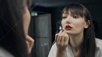 Beautiful attractive woman make up herself in front of the mirror get ready for photoshot and wink her eye to camera