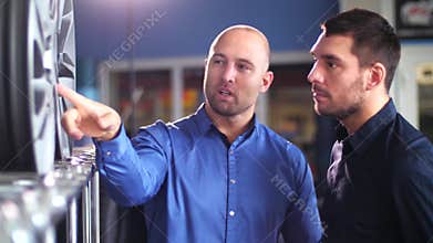 Customer and salesman with car wheels at auto store