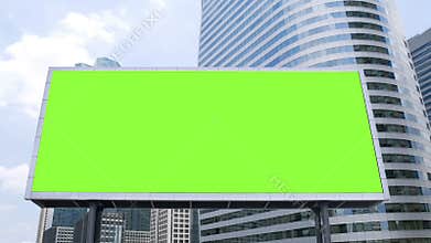 Billboard with a blank green screen mock-up in front of office building in business district on a busy day, time lapse.
