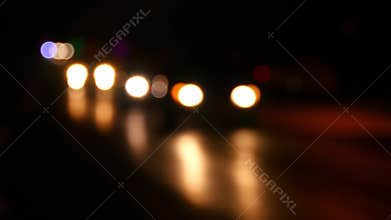 Colorful blurry car headlights glowing in the dark on the road. Blurred focus.