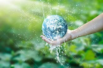 Water pouring on planet earth placed on human hand