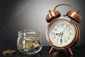 Time to saving concept - jar savings with retro clock on black b
