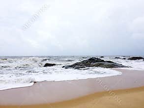 The sandy beaches of Kundapura with rocks and foamy waves