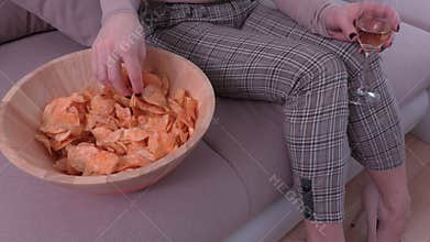 Woman sitting on sofa and eating chips