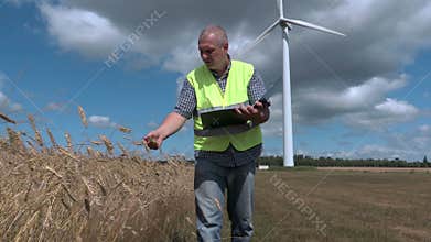 Farmer checking cereals near wind turbine