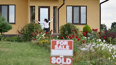 Happy woman in front of their new house