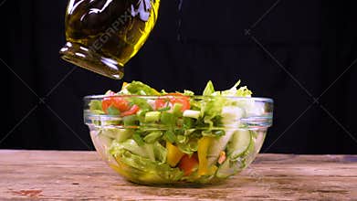 Adding a olive oil to salad in glass bowl
