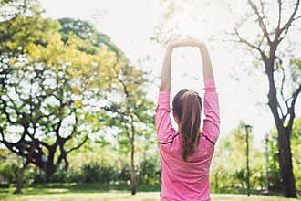 Asian young woman warm up the body stretching before morning exercise and yoga in the park under warm light morning.