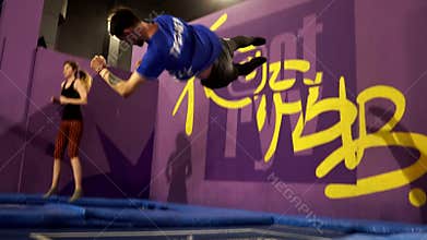 The girl jumps with the coach on the trampoline. Trampoline park.