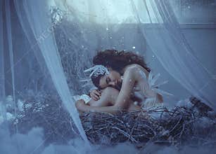 The girl bird sits in her nest, timidly bowing her head and embracing her legs. A nest in a fairy-tale house, near the