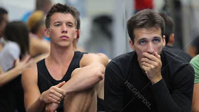 Two attractive men listening a coach on the training in the gym