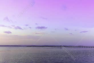 Lake landscape with long jetty by violet sky at dusk