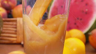 Multifruit juice is poured into a glass. Slow motion.