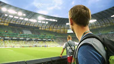 Male soccer fan watching match from tribune at stadium, supporting national team
