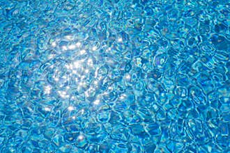 Water ripples texture in swimming pool with sunny glare
