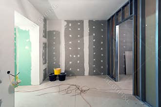 Metal frames and plasterboard drywall for gypsum walls, three buckets and electric wires in apartment is under construction