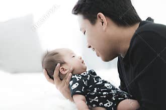 Proud asian father holding his newborn baby at home.