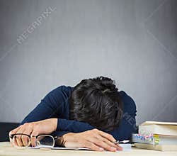 Man sleeping on work wooden desk, study hard and tired concept