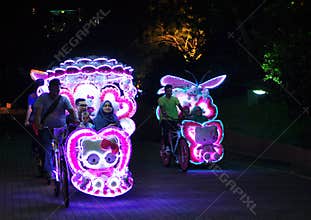 Illuminated decorated trishaw with soft toys at night in Malacca, Malaysia