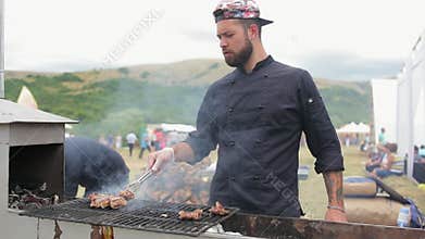 Handsome chef cooks ribs on the grill