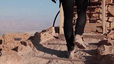 Male legs climbing up on desert stairs. Slow motion. Man steps on desert rocky hill. Back view. Stepping up. Career path