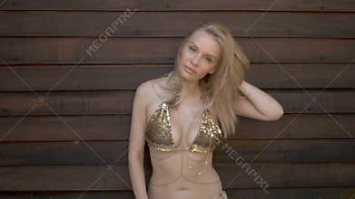 blonde with big breasts in golden bikini posing and smiling