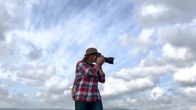 Young woman professional photographer taking pictures of the landscape