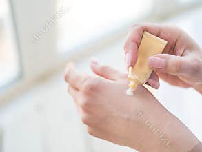 Closeup on woman`s hands applying moisturizing hand-cream on