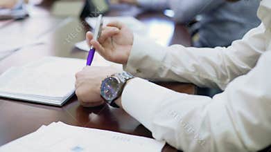 Bored employee sitting at business conference and spinning a pen in his hands