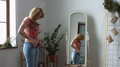 Woman struggling trying to fit into tight jeans