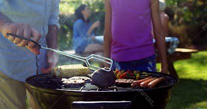 Grandfather and granddaughter preparing barbecue while family having meal 4k