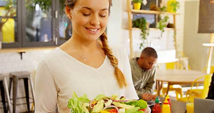 Portrait of beautiful waitress holding salad in plate 4k