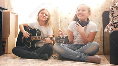 Two female teens playing musical instruments at home