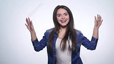 Attractive young woman waving her hands in the air with excitement and laughing