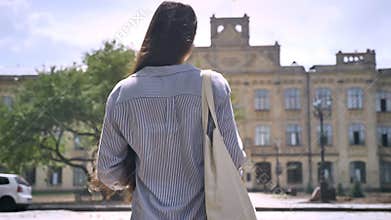 Back view of college student with long hair walking upstairs to university, ready to study