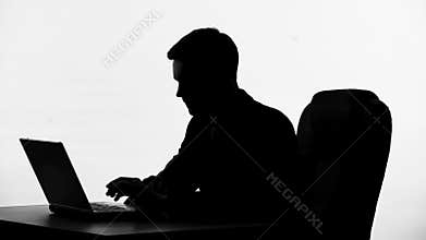 Businessman silhouette sitting in front of laptop, thinking on business proposal