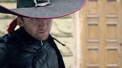 A stylish male cosplayer musketeer, reclines his cloak and prepares for battle