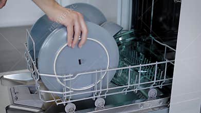 Happy Young Woman Arranging Plates In Dishwasher At Home