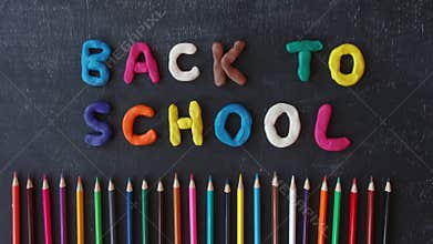 Stop motion hand made plasticine lettering back to school on the blackboard. Fun cartoon rainbow modeling clay. Colored pencils