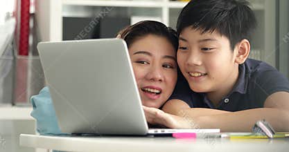 Cute asian mother helping your son doing your homework at home with smile face together.
