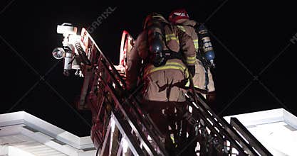 Firefighters ladder climb on roof.
