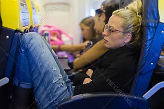 Tired lady napping on airplane.