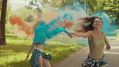 Young girls have fun with colored smoke and jump outdoors in slow motion