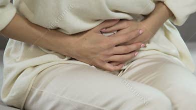 Female having stomach pain, period suffering, pregnancy problem, hands closeup