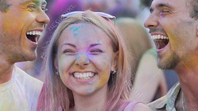 Two young men kissing female friend on cheeks, positive festival atmosphere