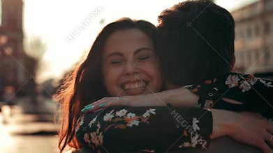 Charming brunette woman running to hug her boyfriend at urban street.